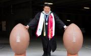 a young man stands next to large footballs 